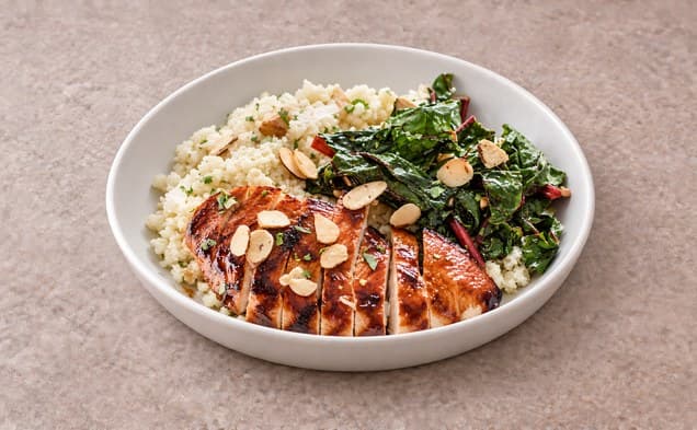 A serving of barbecue chicken cauliflower couscous bowls on a plain white dish